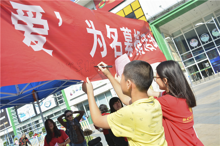 小男孩谢宇星认真为小煜铭写下祝福 李城 摄.JPG